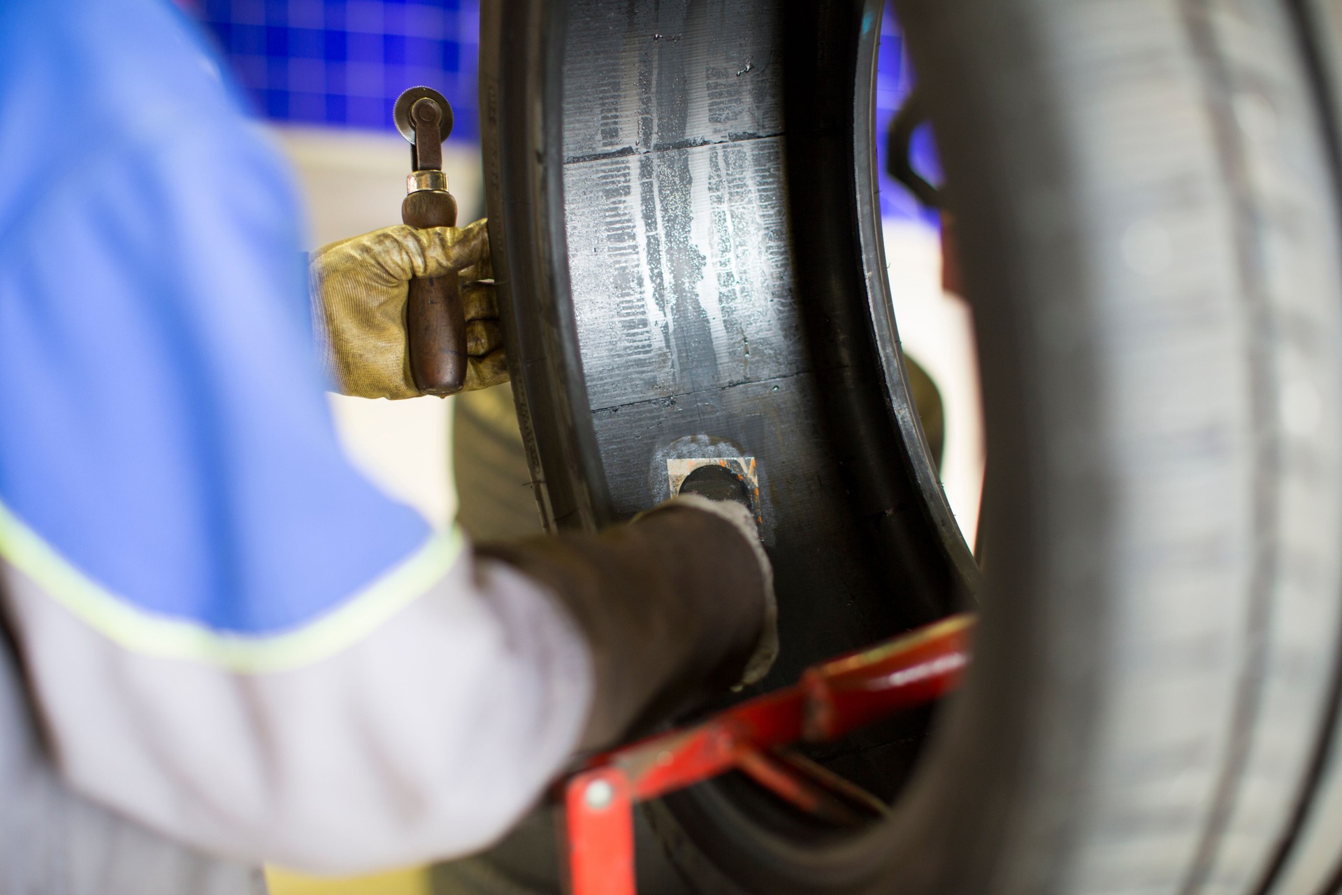 In an auto garage...car mechanic is patching flat tire